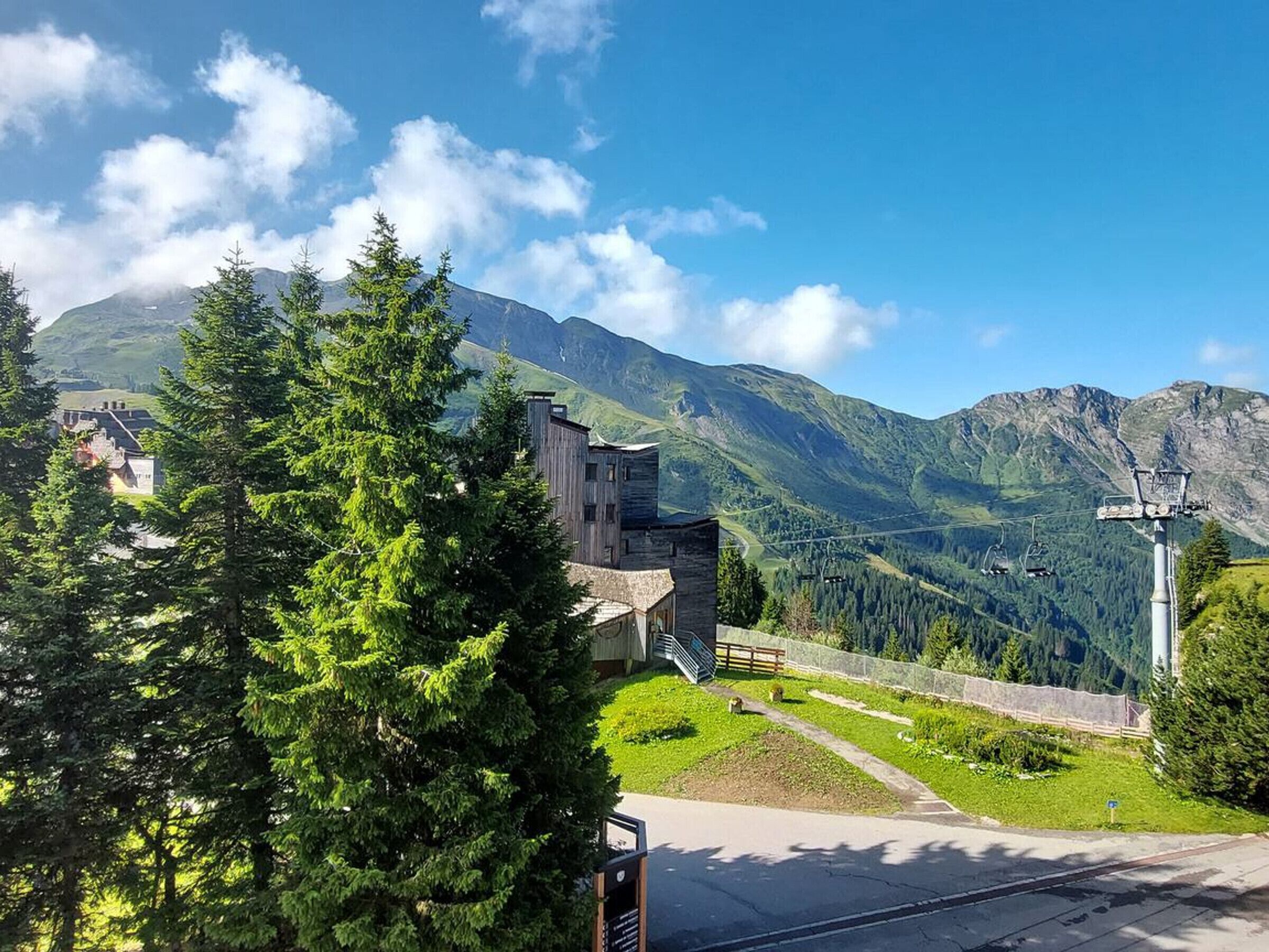 Eine Berghütte mit Steinbau, einer Seilbahn und Blick auf die umliegenden Berge.