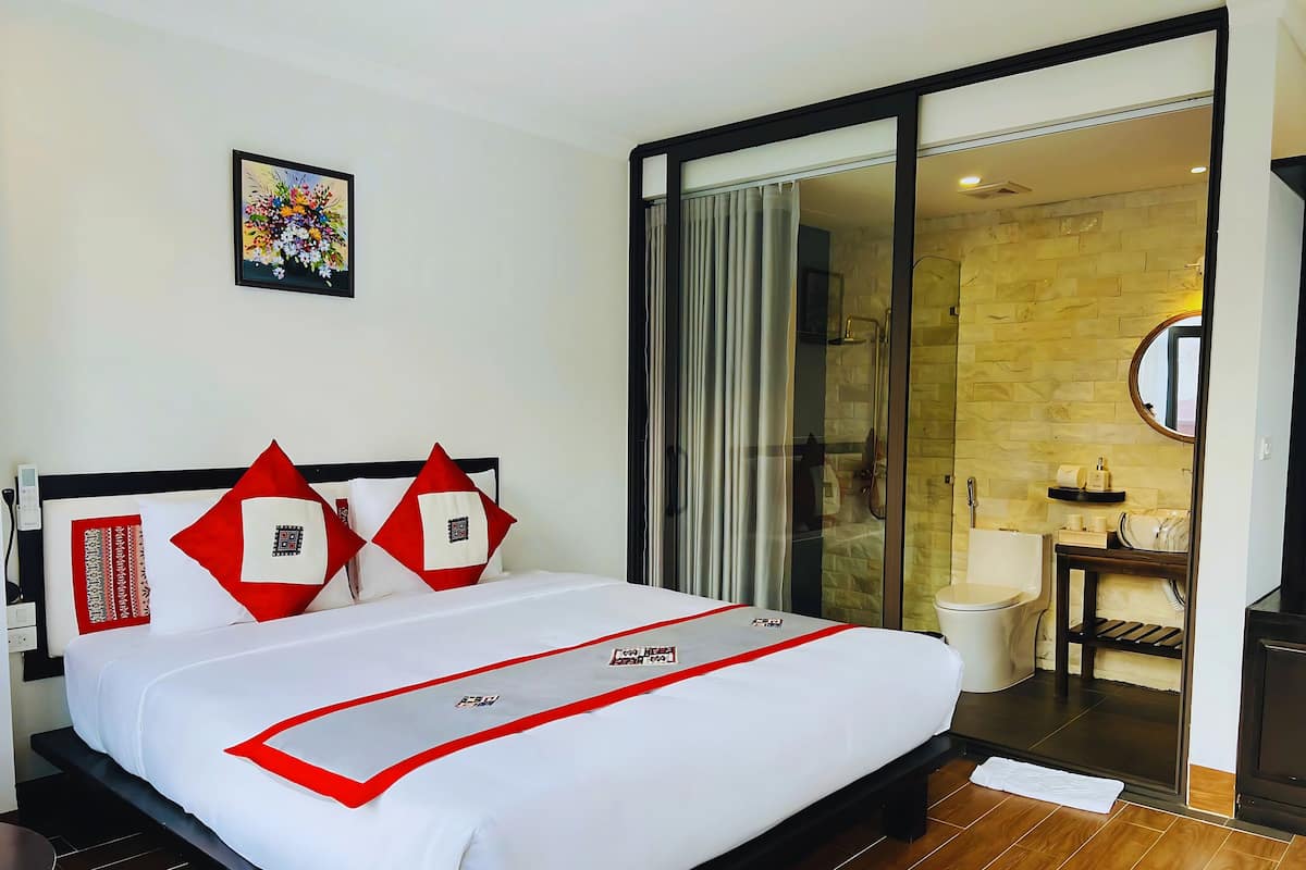 A hotel room with a bed, a bathroom, and a shower area.