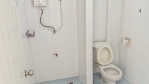 Un baño pequeño con paredes blancas, un inodoro, una ducha y un dispensador de papel higiénico.