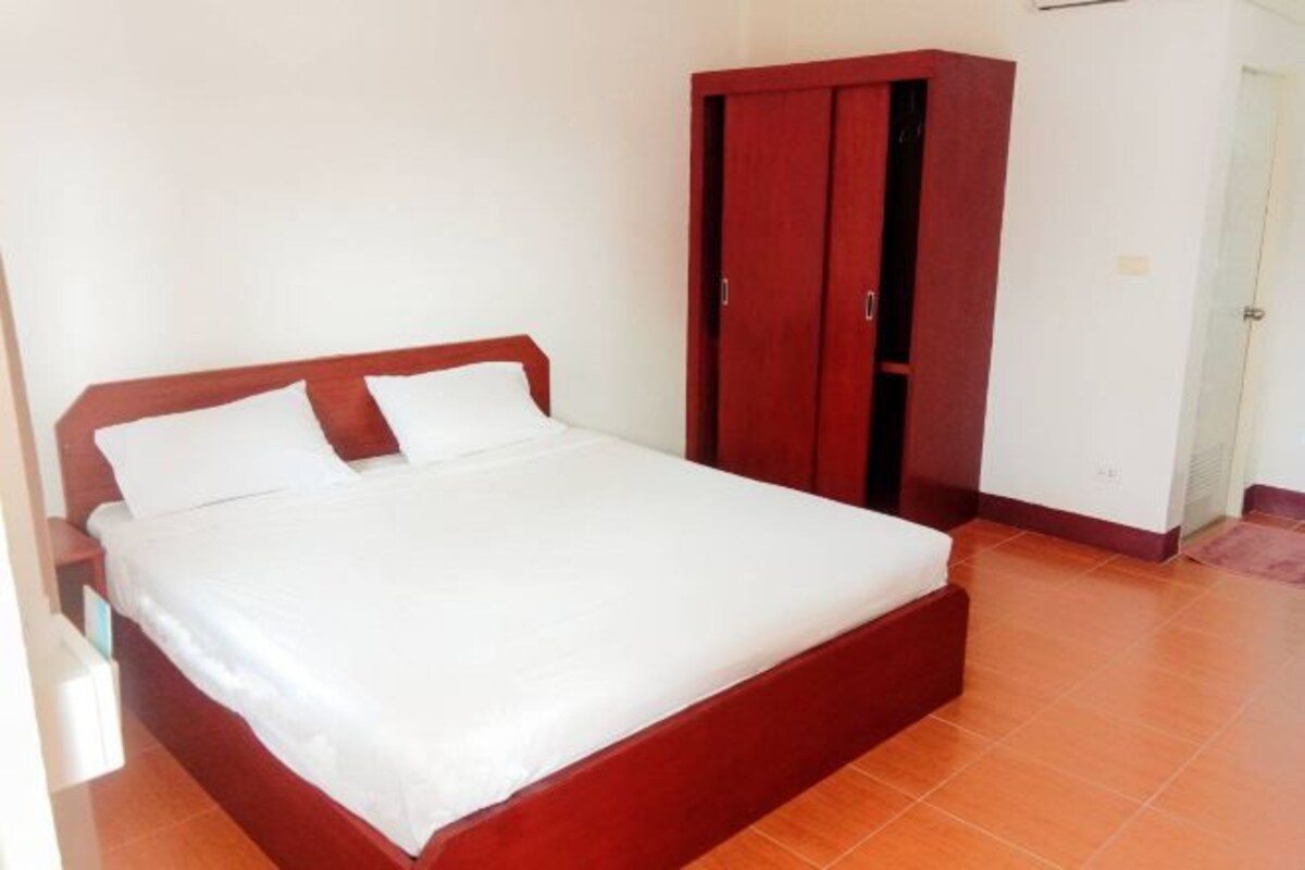 A bedroom with a wooden bed, white bedding, and a red wardrobe.