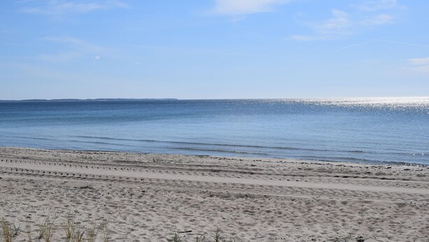 A beach with a clear sky and calm sea.
