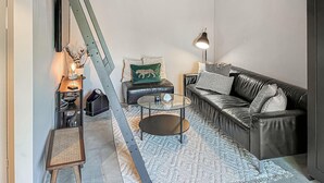 A modern living room with a leather sofa, a glass coffee table, and a patterned rug.