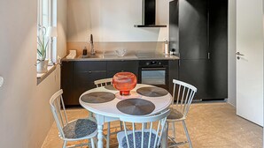 A compact kitchen with a dining table, chairs, and a modern oven.