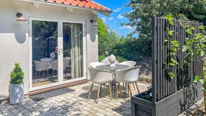 A patio with a table and chairs, a potted plant, and a wooden fence with climbing plants.