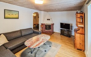 A cozy living room with a sofa, a small table, a TV, a fireplace, and a wooden cabinet.