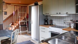A compact kitchen with a refrigerator, stove, sink, and a coffee maker.