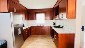 Eine Küche mit Holzausstattung, einem Edelstahlkühlschrank, einem Gasherd und einem Spülbecken.