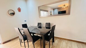 Ein Essbereich mit einem rechteckigen Tisch, sechs Stühlen, einem Ziertelement-Spiegel und einem kleinen runden Spiegel an der Wand.