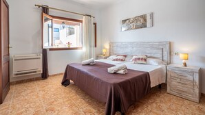 Een hotelkamer met een bed, nachtkastjes, een raam met gordijnen, een radiator en een schilderij aan de muur.