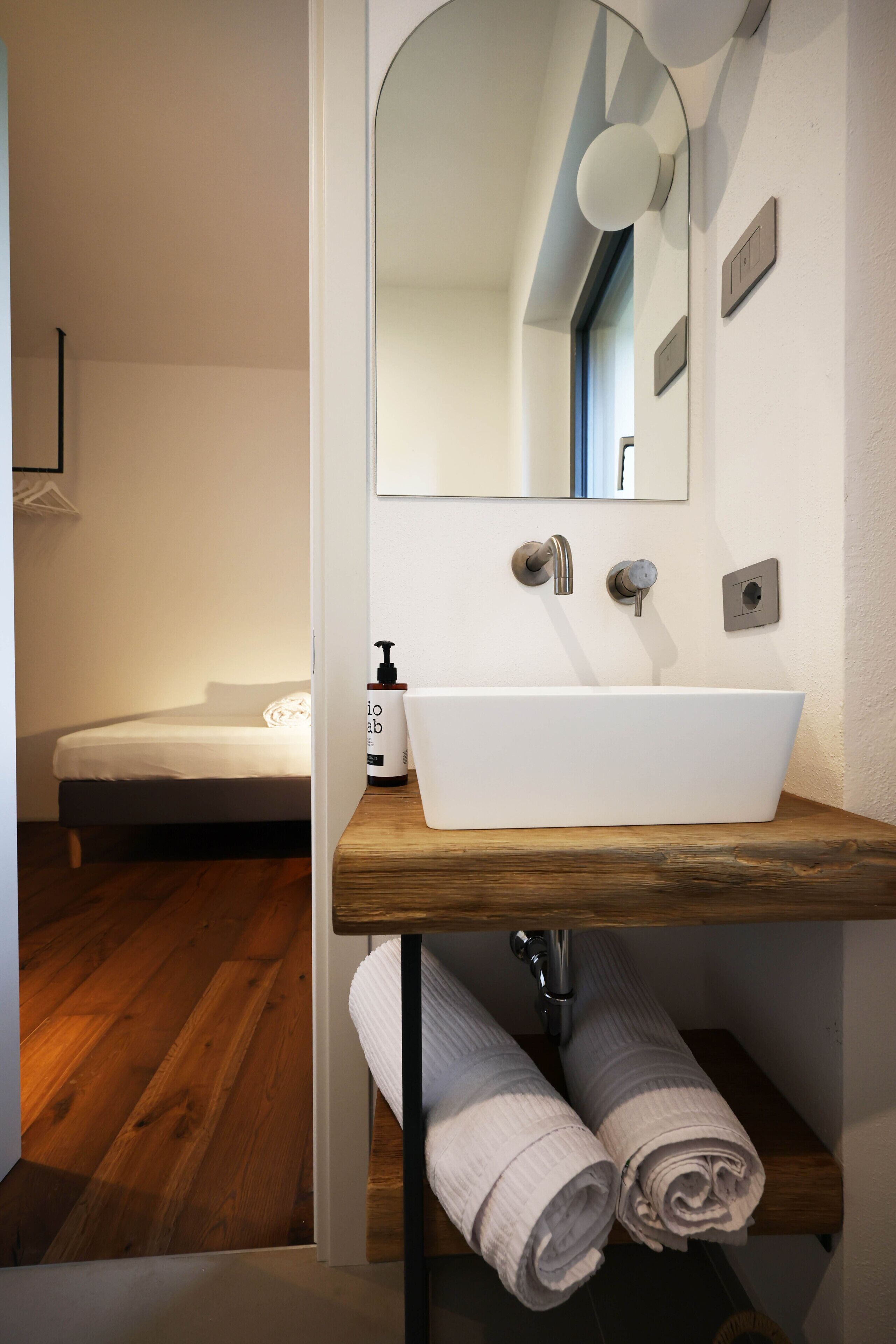 A bathroom with a white sink, wooden countertop, and a mirror above it.