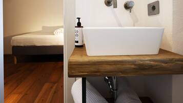 A bathroom with a white sink, wooden countertop, and a mirror above it.