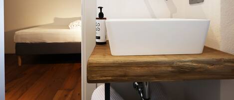 A bathroom with a white sink, wooden countertop, and a mirror above it.