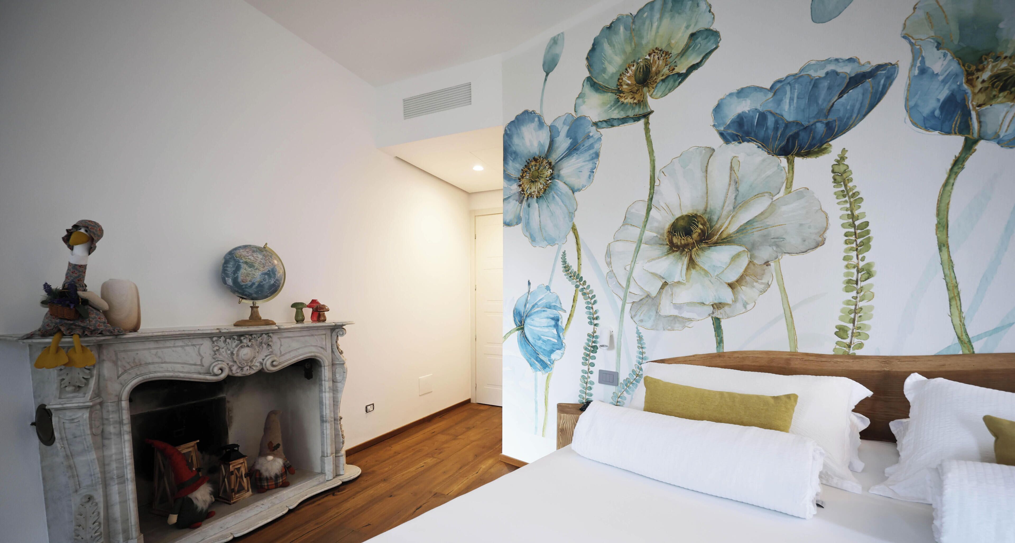 Ein Schlafzimmer mit einem großen Bett, einem Kamin mit Zwergdekorationen und einer Wandmalerei mit Blumenmuster.