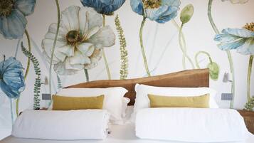 Un dormitorio con cabecera de madera, ropa de cama blanca y un mural floral en la pared.