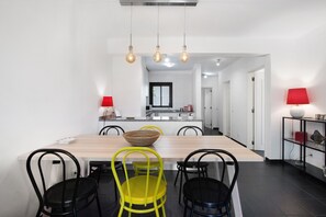 Uma área de refeições moderna com uma mesa de madeira, cadeiras pretas e amarelas e luminárias pendentes.