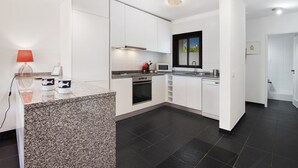 A modern kitchen with white cabinets, a granite countertop, a microwave, an oven, and a dishwasher.