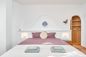 Ein Schlafzimmer mit einem Bett, Kissen, einem runden Dekoelement, zwei Wandleuchten, einem Holzschrank und einer Schmetterlingsdekoration.