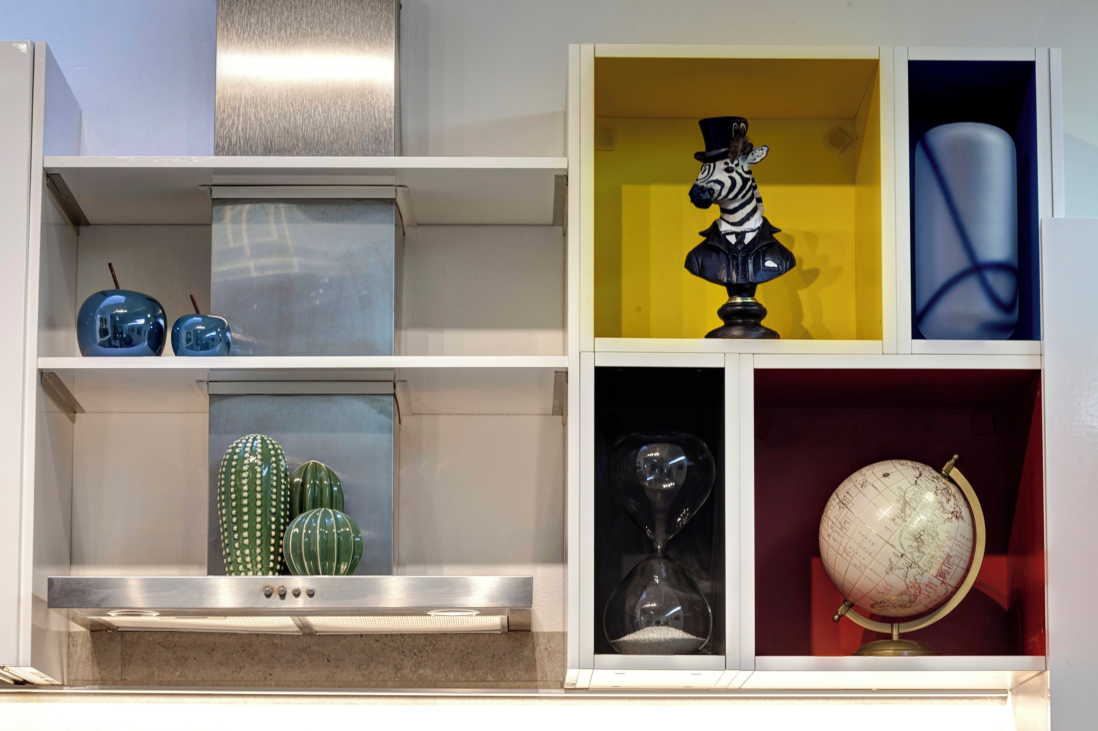 A shelf with decorative items including a globe, a cactus, and a figurine.
