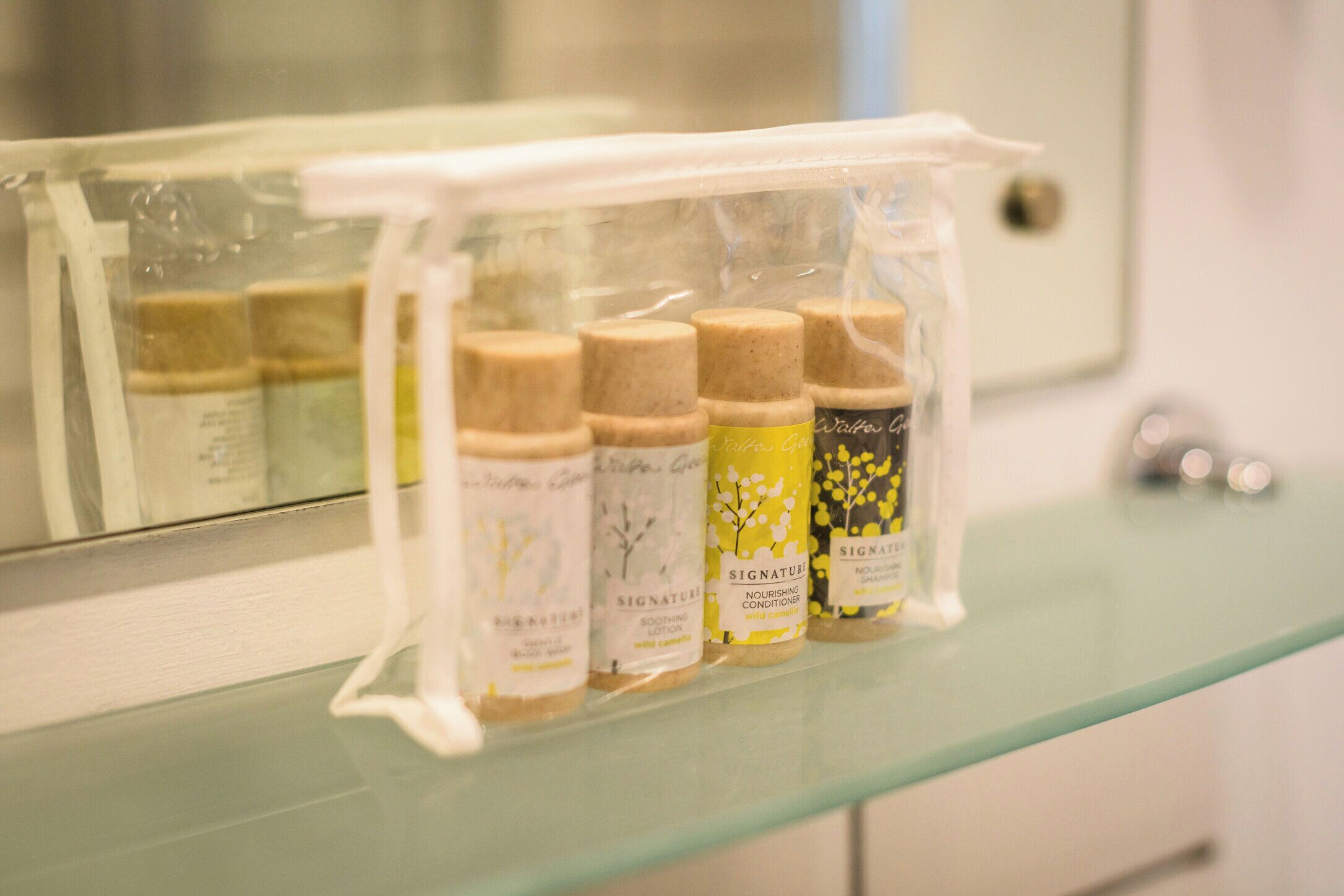 A glass shelf with several bottles of Signature Nourishing Conditioner.