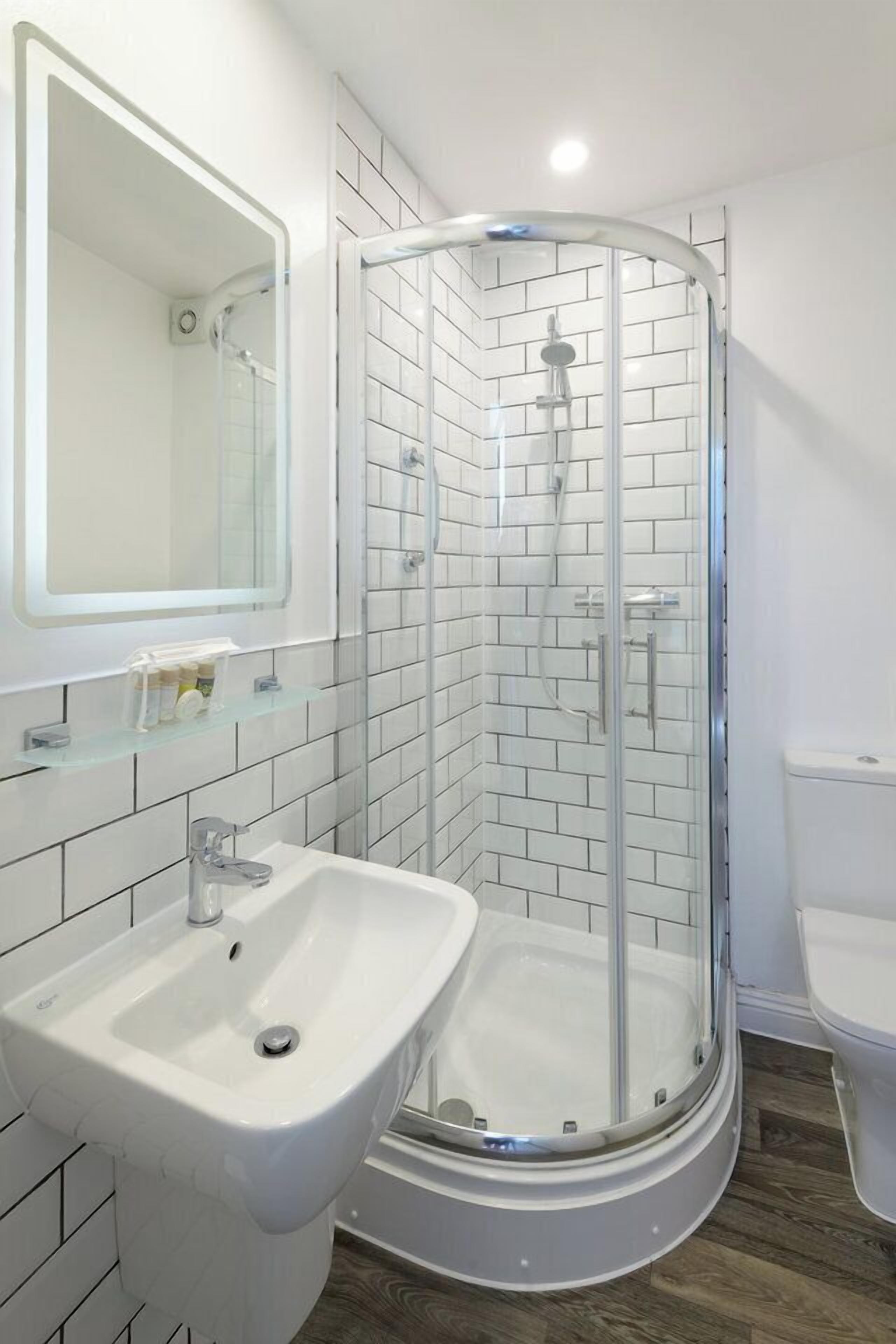 A modern bathroom with a glass-enclosed shower, a white sink, and a toilet.