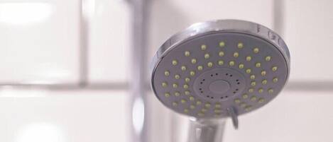 A showerhead with multiple nozzles, attached to a chrome faucet, against a tiled wall.