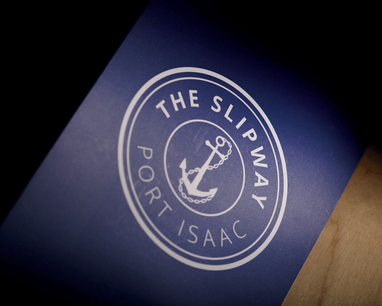A logo with the text "The Slipway Port Isaac" and an anchor symbol.