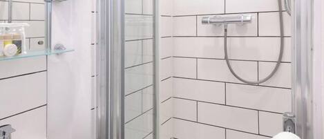 A modern bathroom with a glass shower enclosure, a white sink, and a towel rack.