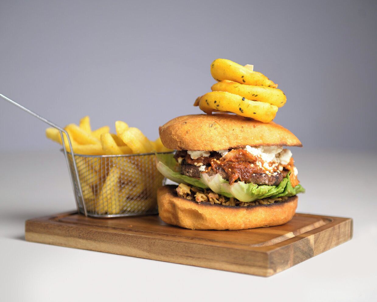 A burger with fries on a wooden board.