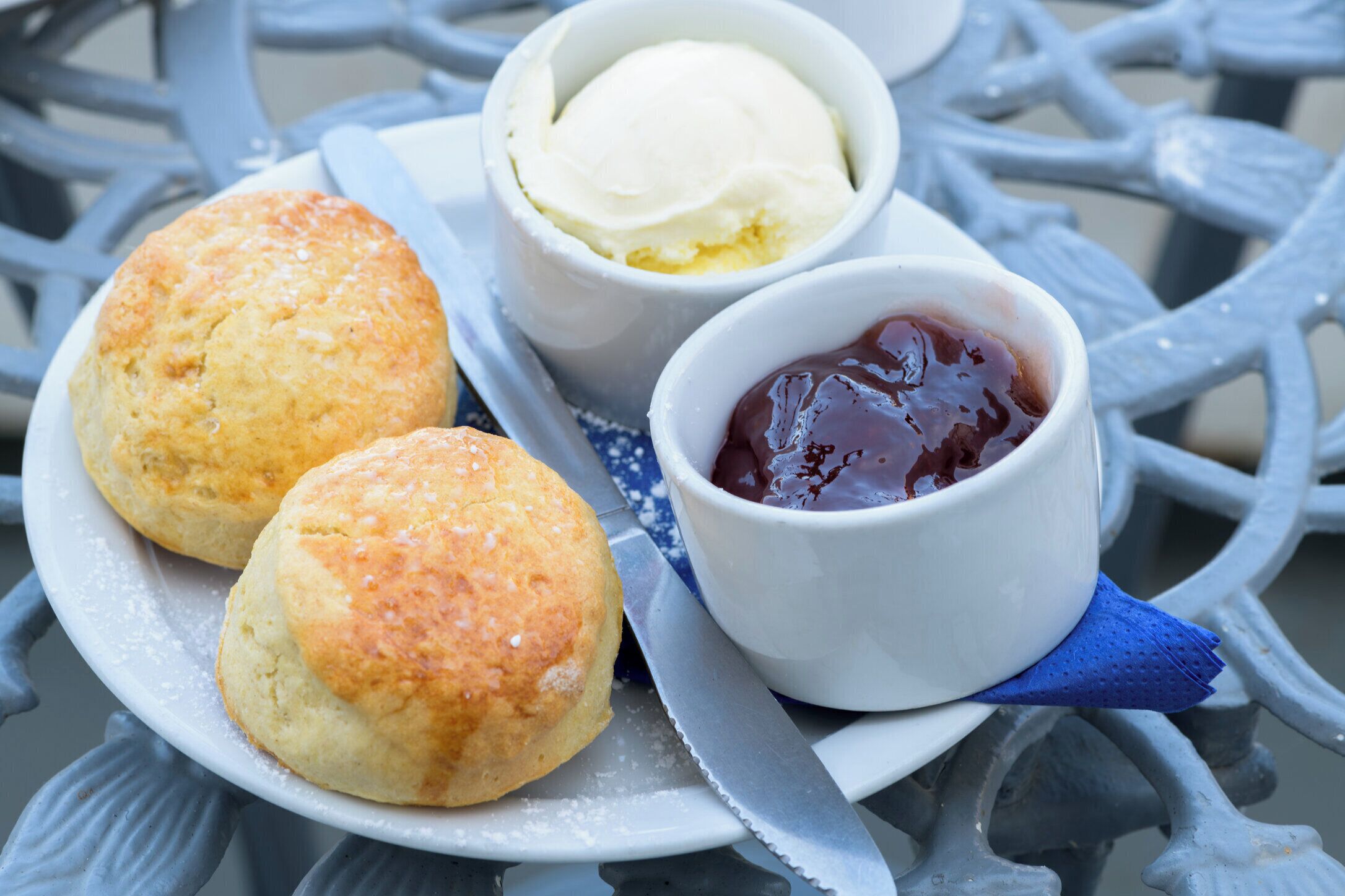 A plate with two biscuits and a cup of ice cream, accompanied by a small bowl of jam.