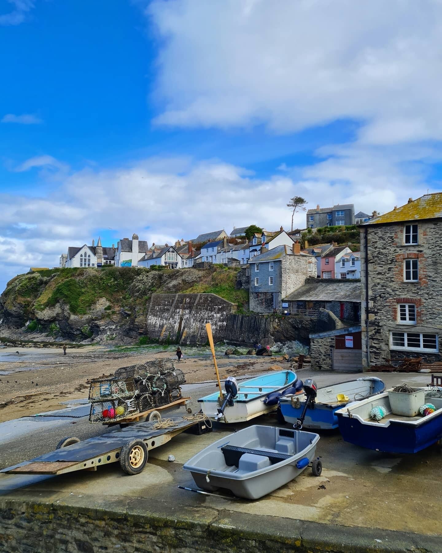 A coastal village with stone buildings, a beach, and several boats.