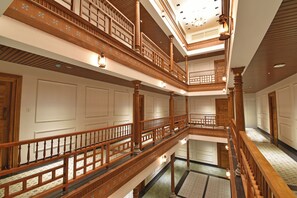 A multi-level interior with wooden railings and a patterned floor. - A K G Hotel (Puducherry)