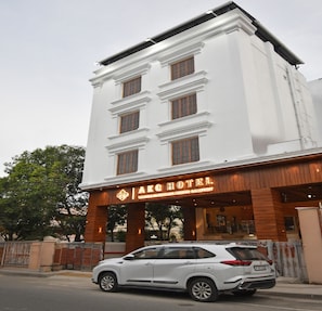 A white building with a sign reading "AKGHOTEL" and a car parked in front. - A K G Hotel (Puducherry)