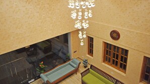 A spacious living area with a large sofa, a coffee table, and a hanging light fixture. - A K G Hotel (Puducherry)