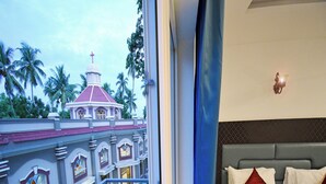 A hotel room with a balcony overlooking a building with a dome and palm trees. - A K G Hotel (Puducherry)