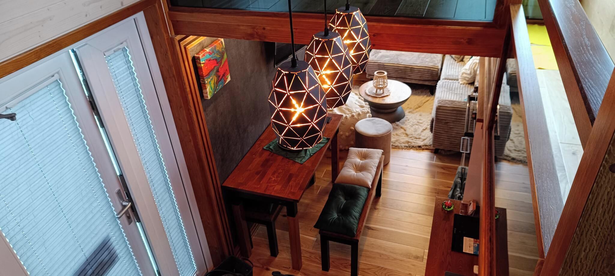Een gezellig interieur met een houten eettafel, twee bankjes en een hanglamp.