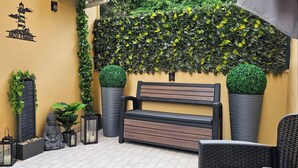 A bench with a cushion, surrounded by potted plants and a wall with a climbing plant. - Love nest with Jacuzzi and Terrace on the Port of Anzio (Anzio)