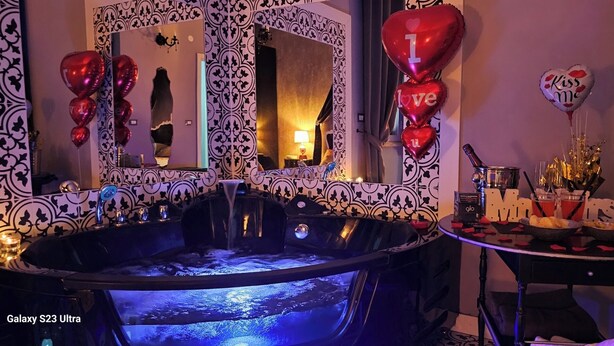 A luxurious bathroom with a large bathtub, a mirror with a decorative frame, and heart-shaped balloons. - Love nest with Jacuzzi and Terrace on the Port of Anzio (Anzio)