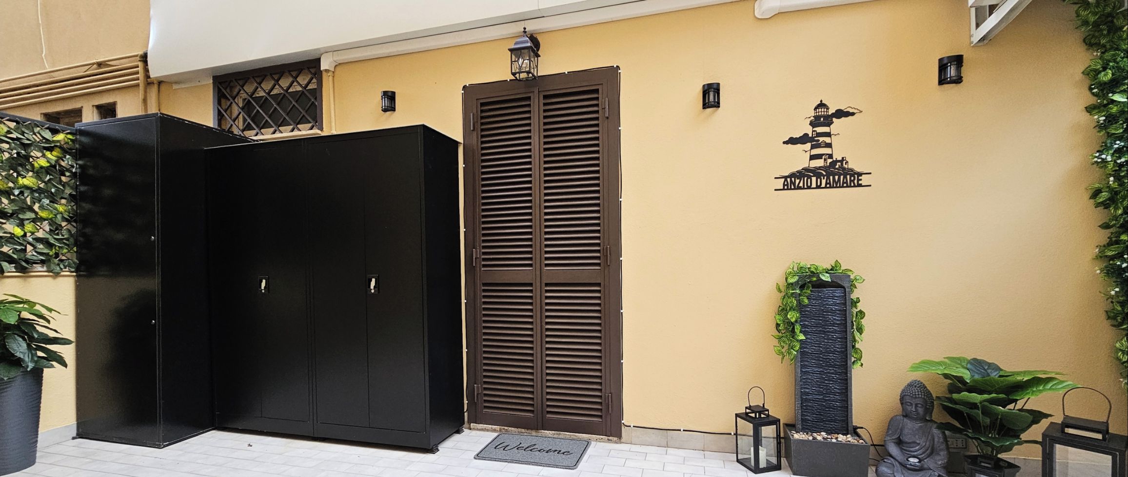 Ein schwarzer Kleiderschrank, eine braune Tür und eine Fußmatte vor einem Gebäude.