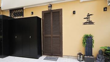 Ein schwarzer Kleiderschrank, eine braune Tür und eine Fußmatte vor einem Gebäude.