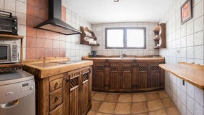 A kitchen with wooden cabinets, a built-in oven, a microwave, and a window above the sink. - Callejón del Pozo I. (Gálvez)