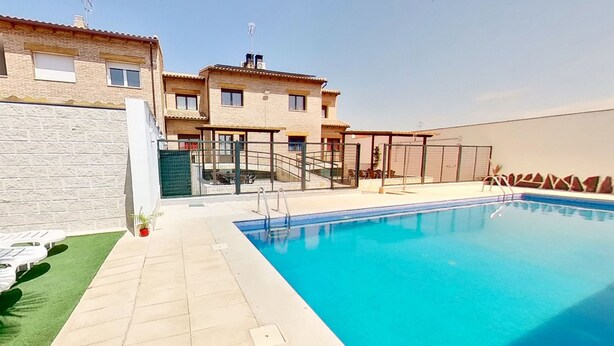 A swimming pool with a clear blue water, a stone wall, and a building with multiple windows and balconies. - Callejón del Pozo I. (Gálvez)