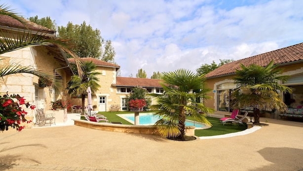 A courtyard with a swimming pool, palm trees, and a building with a tiled roof. - Périgord Romantique, Guest Rooms 'Le Pré Fleuri' with Pool in the Heart of Ribéracois (Saint-Sulpice-de-Roumagnac)