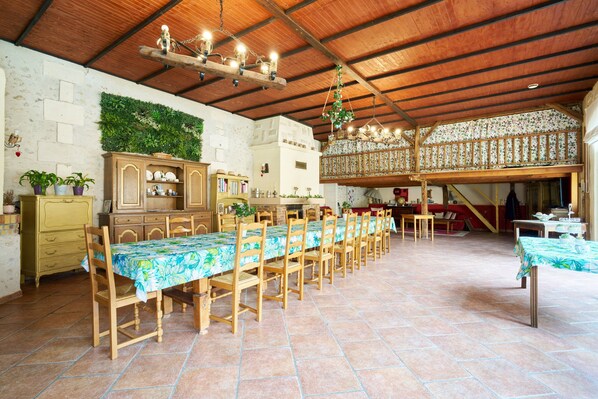 A dining area with a long wooden table, chairs, a hanging light fixture, and a decorative wall. - Périgord Romantique, Guest Rooms 'Le Pré Fleuri' with Pool in the Heart of Ribéracois (Saint-Sulpice-de-Roumagnac)