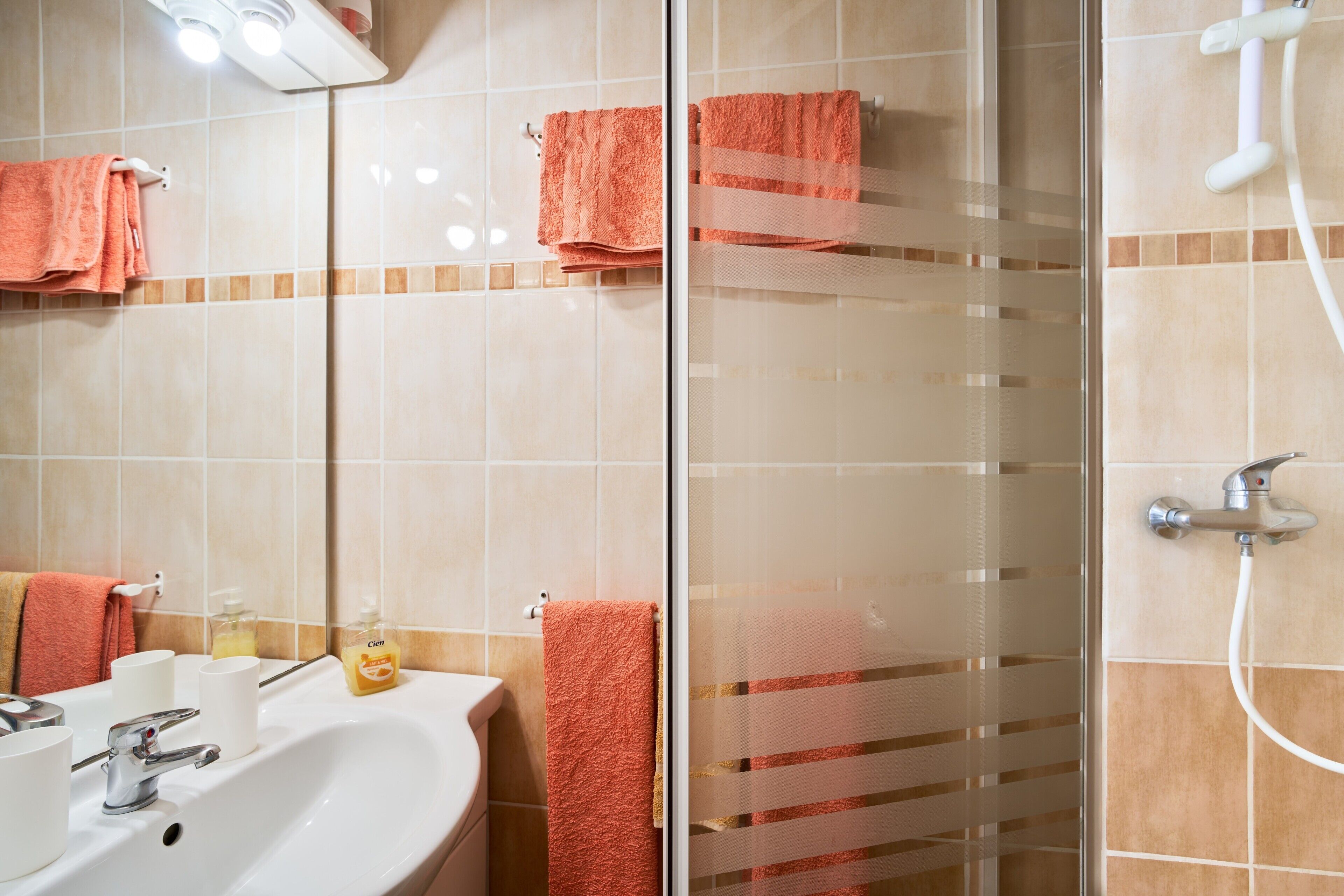 Une salle de bain avec un lavabo, un miroir et deux serviettes accrochées au mur.