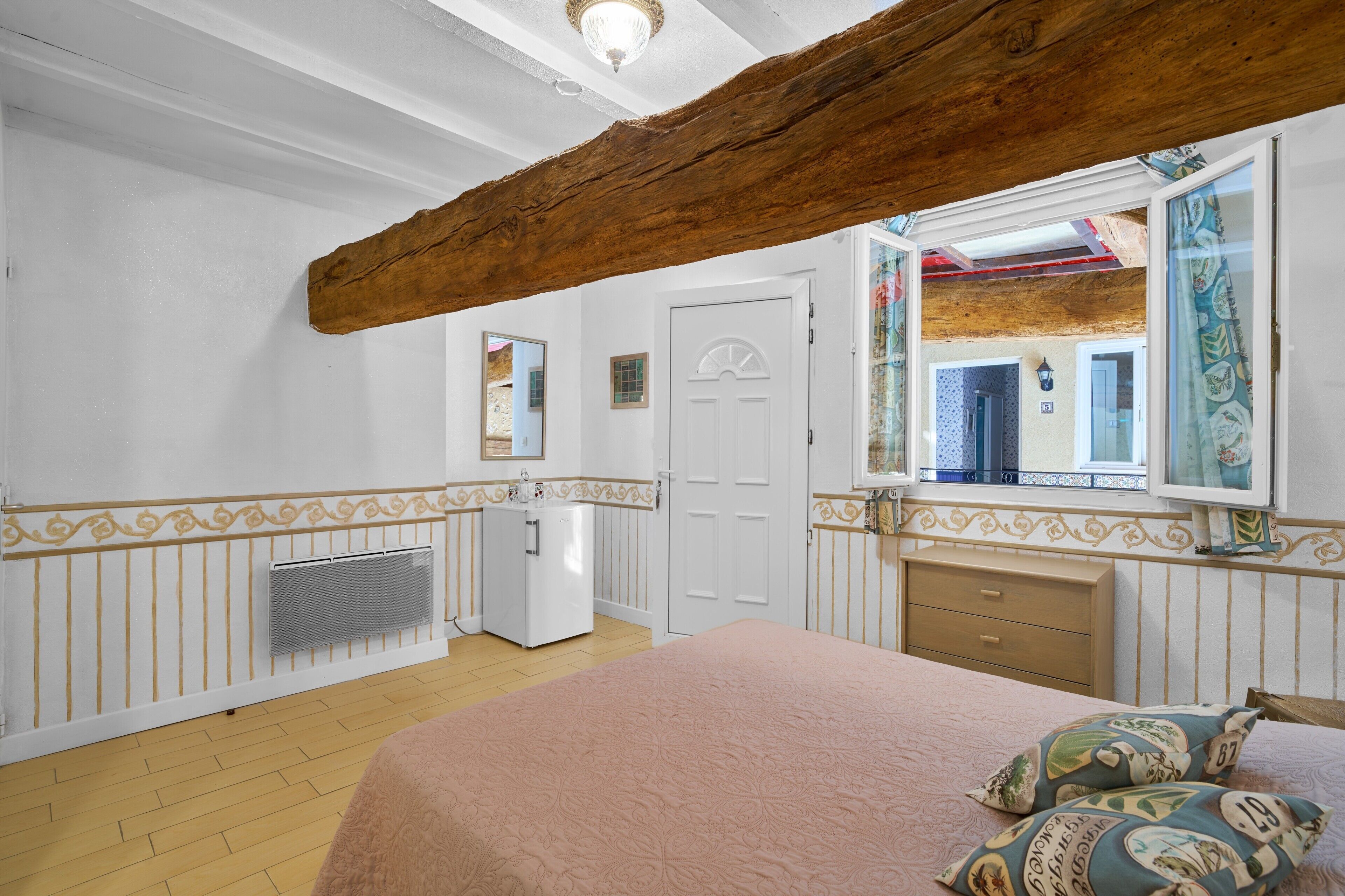 Une chambre à coucher avec un lit, une commode, un miroir et une porte.