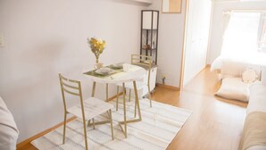 Un comedor con una mesa redonda, cuatro sillas, un jarrón con flores y una estantería.