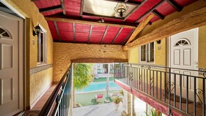 A balcony with a red ceiling, a pool, and a view of the pool area.
