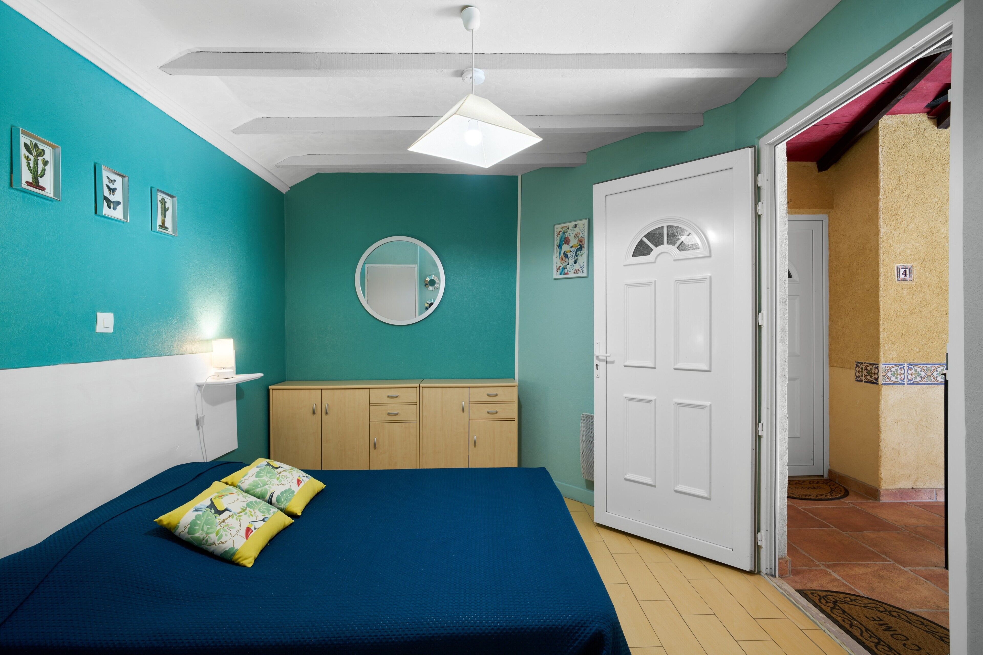 Un dormitorio con cama, armario, espejo y puerta que da a otra habitación.