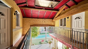 Ein Balkon mit roter Decke, einem Pool und Blick auf das Pool-Areal.