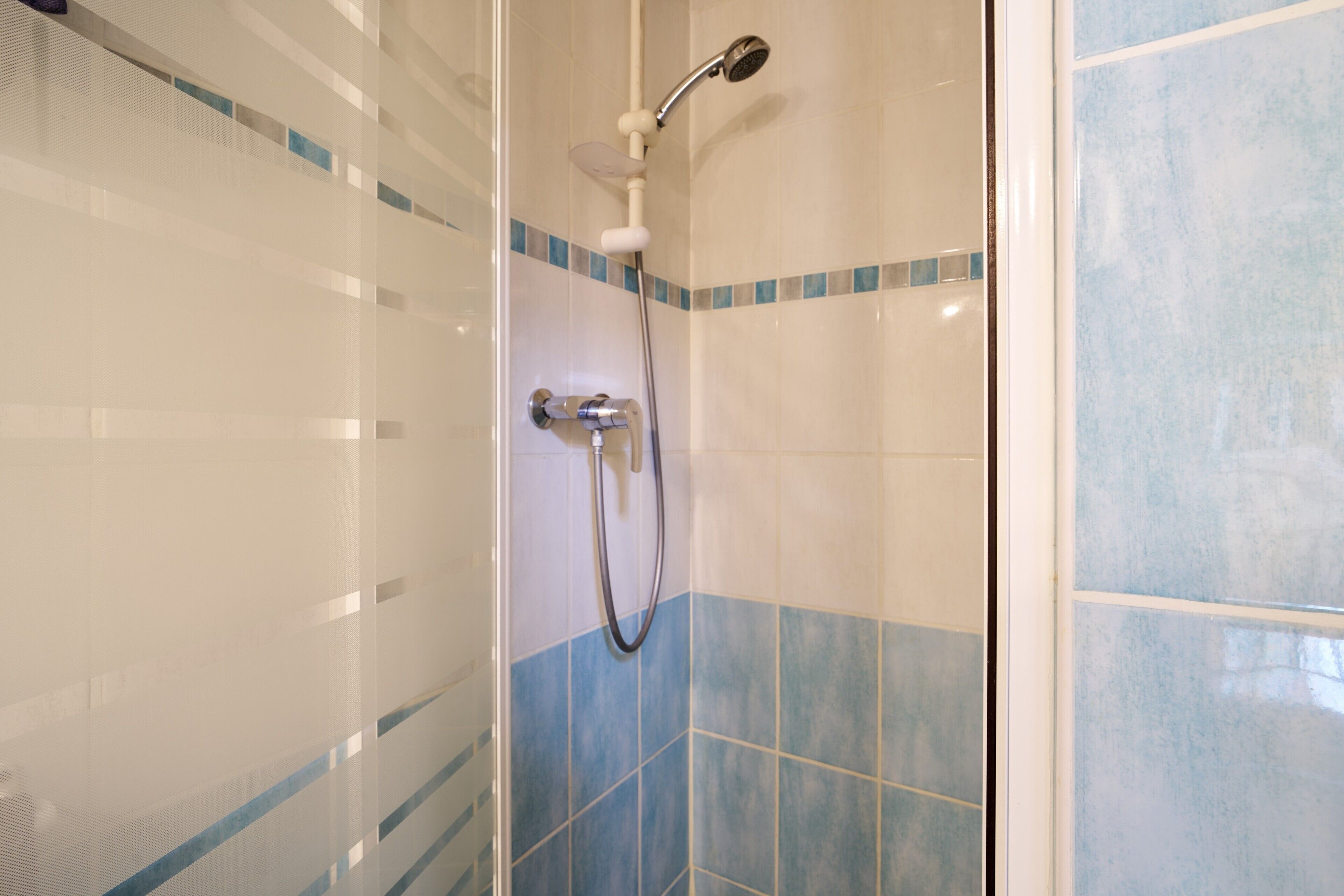 Eine Dusche mit Handbrause und Armaturen an der Wand.